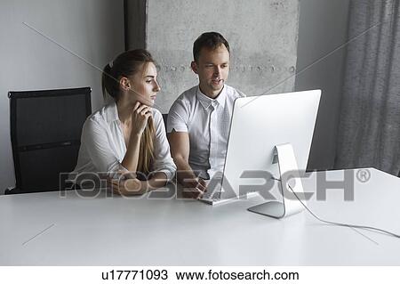 Stock Image - Coworkers working together at desktop computer. Fotosearch