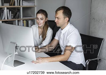 Coworkers working together at desktop computer View Large Photo Image Stock Photo - Coworkers working together at desktop computer. Fotosearch