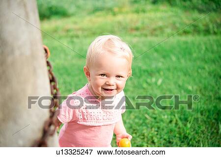 Stock Photo - Cute female toddler in garden, portrait. Fotosearch