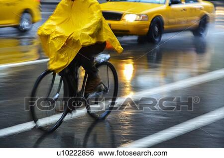 Cyclist in yellow poncho during rain in New York City, USA View Large Photo Image Stock Photograph - Cyclist in yellow poncho during rain in New York City, USA. Fotosearch