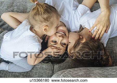 Daughters kissing their mother's cheek View Large Photo Image Stock Image - Daughters kissing their mother's cheek. Fotosearch