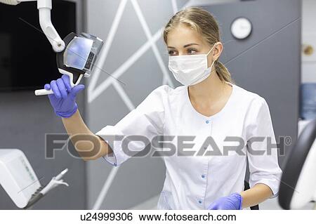 Stock Photograph - Dental assistant holding light. Fotosearch