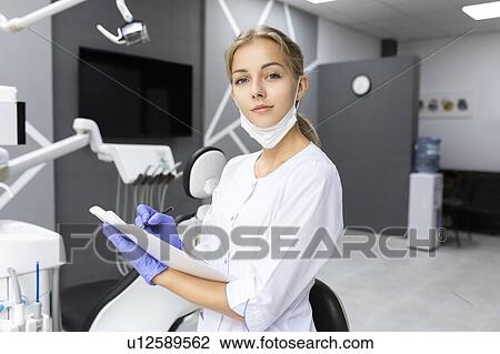 Stock Image - Dental assistant writing notes. Fotosearch