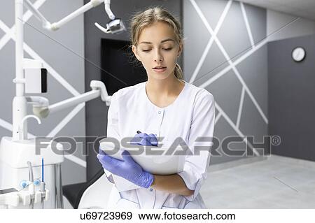 Stock Photo - Dental assistant writing notes. Fotosearch