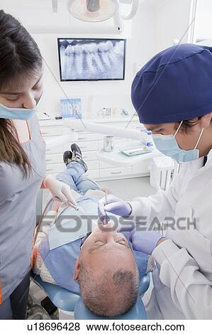 Dentist and hygienist cleaning patient's teeth View Large Photo Image Stock Photo - Dentist and hygienist cleaning patient's teeth. Fotosearch