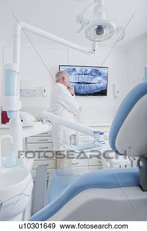 Stock Photo - Dentist examining X-ray on television screen. Fotosearch