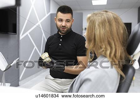 Picture - Dentist showing patient model teeth. Fotosearch