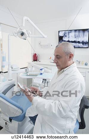 Dentist using digital tablet in dentist's surgery View Large Photo Image Stock Image - Dentist using digital tablet in dentist's surgery. Fotosearch