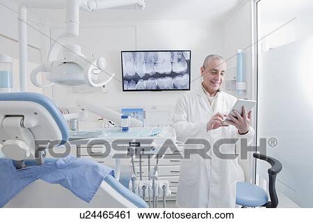 Dentist using digital tablet in dentist's surgery View Large Photo Image Stock Image - Dentist using digital tablet in dentist's surgery. Fotosearch