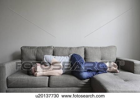 Stock Image - Depressed mature man lying on sofa. Fotosearch