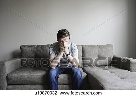 Stock Image - Depressed mature man sitting on couch. Fotosearch
