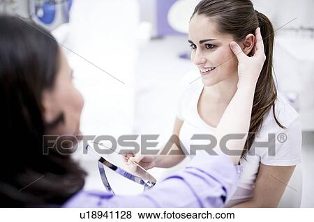 Stock Photo - Dermatologist examining patient's facial skin, close-up.. Fotosearch