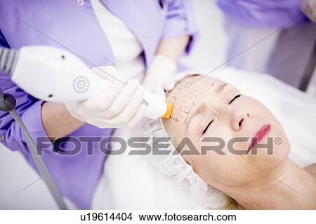 Dermatologist giving thermage treatment to mature woman's forehead to soften wrinkles. View Large Photo Image Picture - Dermatologist giving thermage treatment to mature woman's forehead to soften wrinkles.. Fotosearch