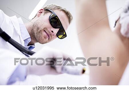 Stock Photography - Dermatologist using laser hair removal treatment for under arms. Laser hair removal permanently destroys the root of the hair follicles by using pulses of light.. Fotosearch
