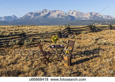 Stock Photo - Dining table and chairs in field by mountain in Stanley, Idaho. Fotosearch