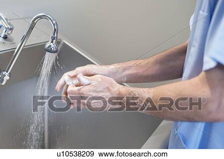 Doctor cleaning hands with soap and water in hospital. View Large Photo Image Stock Photo - Doctor cleaning hands with soap and water in hospital.. Fotosearch