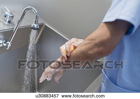 Doctor cleaning hands with soap and water in hospital. View Large Photo Image Stock Photo - Doctor cleaning hands with soap and water in hospital.. Fotosearch
