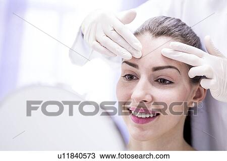 Doctor examining young woman's forehead. View Large Photo Image Stock Image - Doctor examining young woman's forehead.. Fotosearch