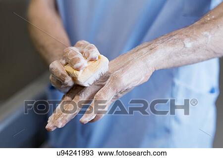 Stock Image - Doctor scrubbing hands with brush in hospital.. Fotosearch