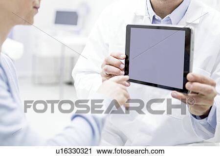 Stock Image - Doctor showing digital tablet to patient.. Fotosearch
