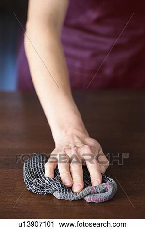 Stock Image - Domestic hygiene. Close-up of hand cleaning a household surface with a cloth.. Fotosearch