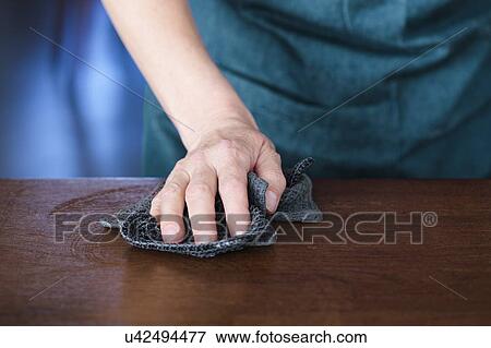 Stock Photo - Domestic hygiene. Close-up of hand cleaning a household surface with a cloth.. Fotosearch