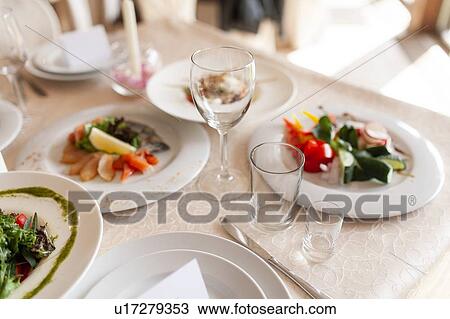 Stock Image - Drinking glasses and food on dining table during wedding. Fotosearch
