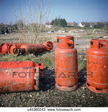 Stock Image - Dumped gas cylinders on urban wasteland near a residential area in Liverpool, UK.. Fotosearch