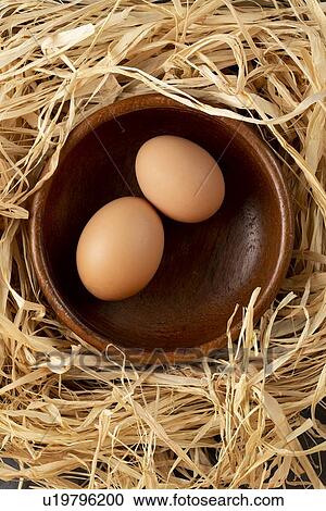 Stock Image - Eggs in wooden bowl on straw. Fotosearch