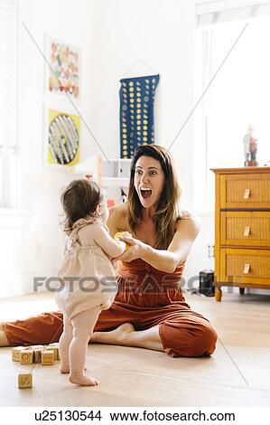Excited woman holding her baby daughter's hands View Large Photo Image Picture - Excited woman holding her baby daughter's hands. Fotosearch