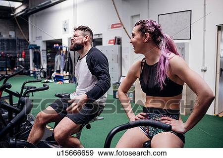 Exhausted young woman and man training together on gym exercise bikes, taking a break View Large Photo Image Stock Photo - Exhausted young woman and man training together on gym exercise bikes, taking a break. Fotosearch