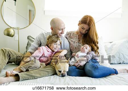 Stock Photo - Family and their dog on bed. Fotosearch