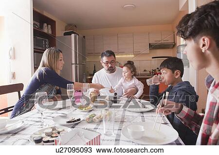 Stock Image - Family eating sushi at dining table. Fotosearch
