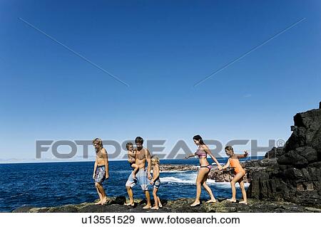 Family walking on rocks by sea View Large Photo Image Stock Photo - Family walking on rocks by sea. Fotosearch