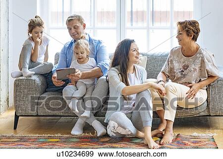 Stock Photo - Family with digital tablet on sofa. Fotosearch