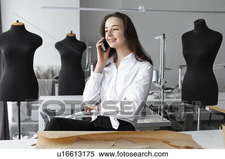Fashion designer talking on smartphone in studio View Large Photo Image Stock Photography - Fashion designer talking on smartphone in studio. Fotosearch