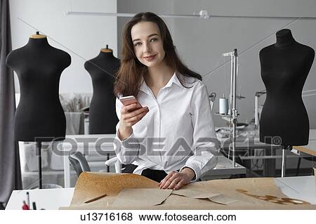 Stock Photo - Fashion designer using smartphone in studio. Fotosearch