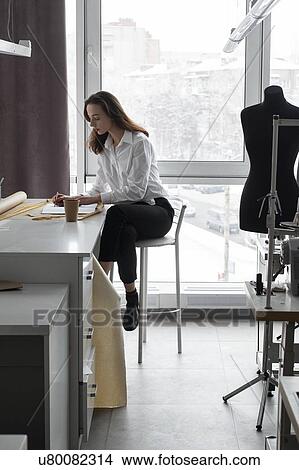 Picture - Fashion designer working at desk in studio. Fotosearch