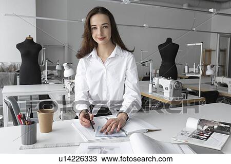 Stock Image - Fashion designer working at desk in studio. Fotosearch