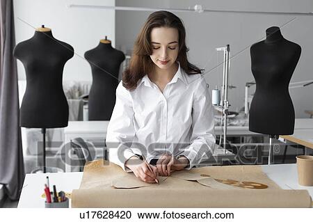 Stock Image - Fashion designer working at desk in studio. Fotosearch