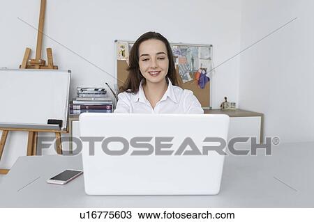 Stock Image - Fashion designer working at laptop. Fotosearch