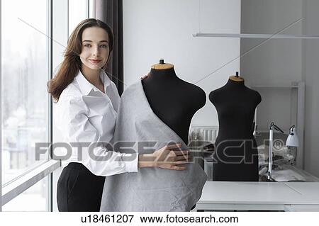 Stock Photo - Fashion designer working with dressmaker's model in studio. Fotosearch