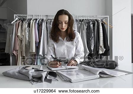 Picture - Fashion designer writing in notebook. Fotosearch