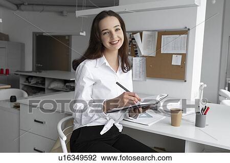 Stock Image - Fashion designer writing in notebook. Fotosearch