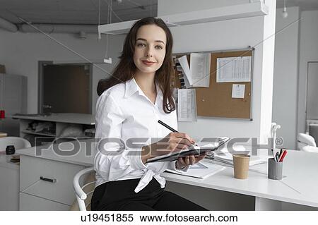 Stock Photography - Fashion designer writing in notebook. Fotosearch