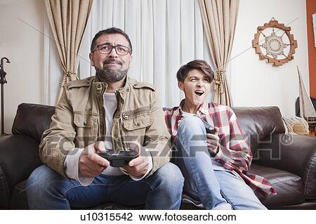 Stock Image - Father and son playing video game. Fotosearch