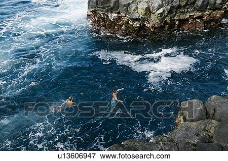 Stock Photo - Father and son swimming in sea by cliffs. Fotosearch