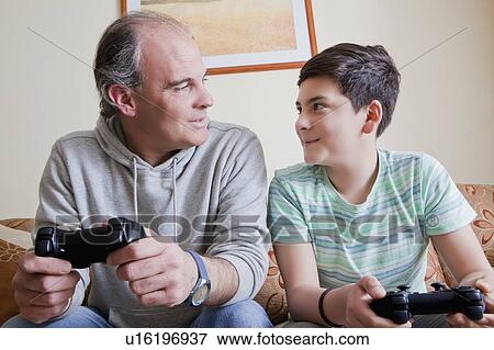 Father and teenage son playing video game View Large Photo Image Stock Photo - Father and teenage son playing video game. Fotosearch
