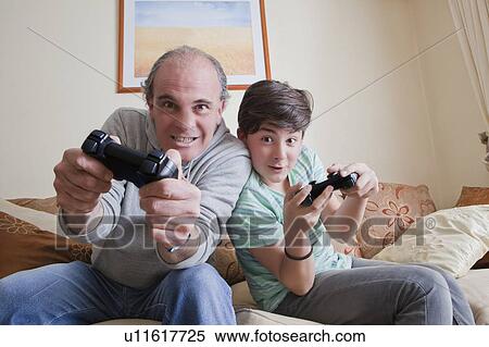 Father and teenage son playing video game View Large Photo Image Stock Photography - Father and teenage son playing video game. Fotosearch