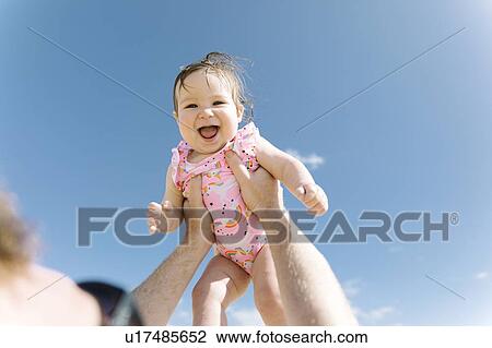 Stock Image - Father holding his baby girl aloft. Fotosearch